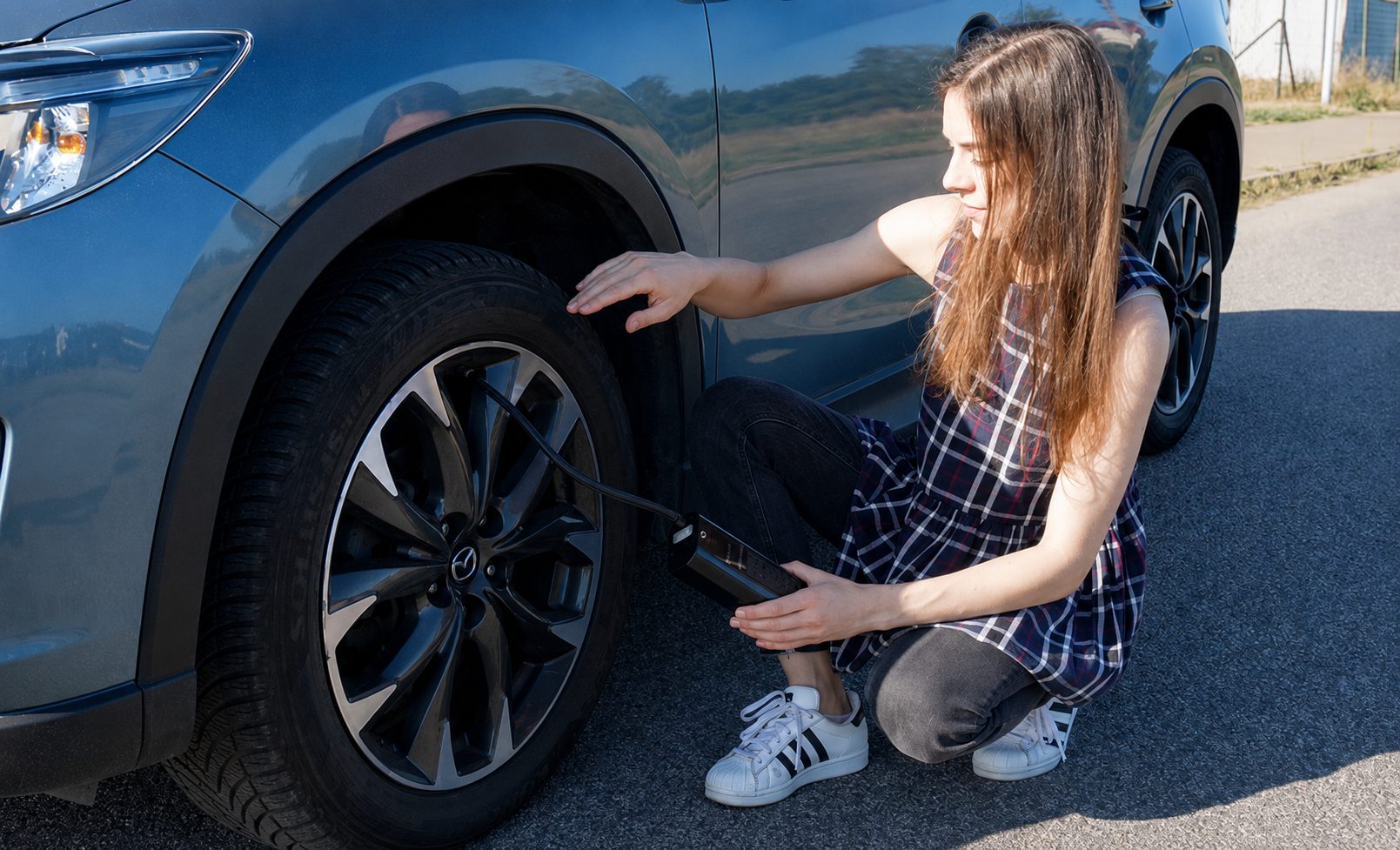 Automobiliste qui regonfle un pneu au bord de la route avec le gonfleur sans fil TireHero